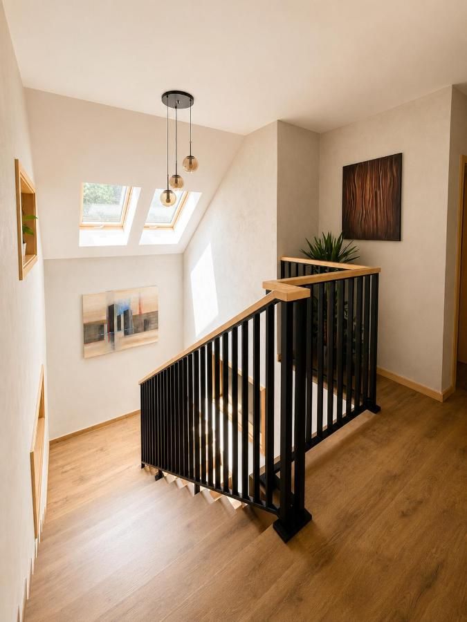 Klatka schodowa z czarną balustradą i oknami dachowymi